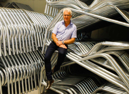 Fotografie von Jehannes Bottema, CEO des Unetrnehmens Spinder, wie er halb auf einer Reihe aufgestapelter Trenngitter sitzt.